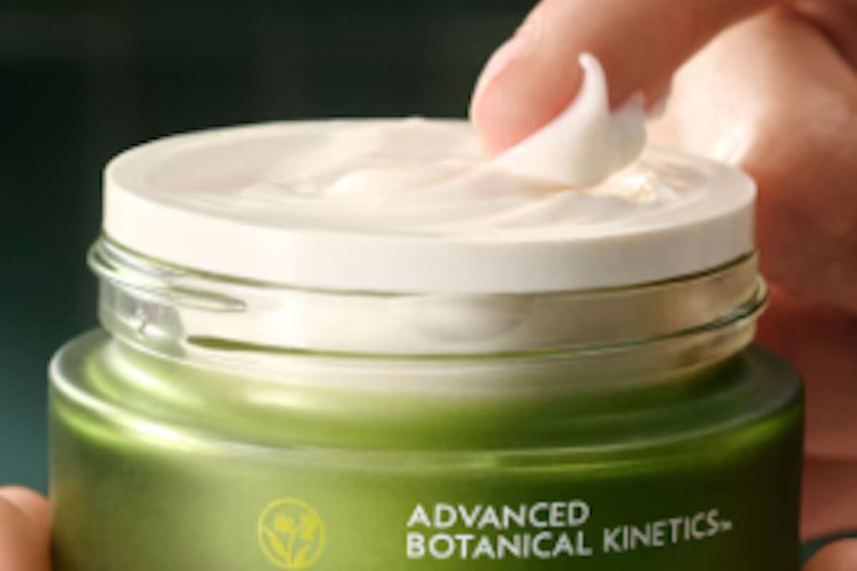 Close-up of a dollop of rich Aveda Botanical Kinetics cream on a fingertip, showing its smooth, hydrating texture